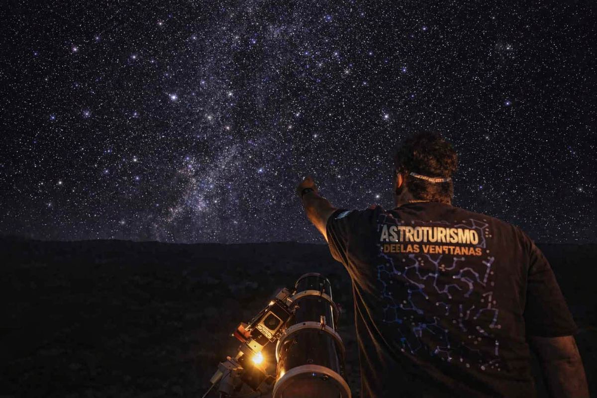 Guía señalando el cielo estrellado durante una salida de astroturismo