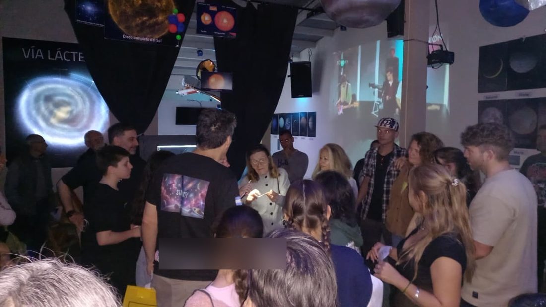 Grupo de visitantes en la sala principal de la exposición, con una pantalla de la Vía Láctea